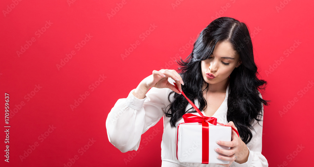 快乐的年轻女人在坚实的背景上拿着一个礼盒