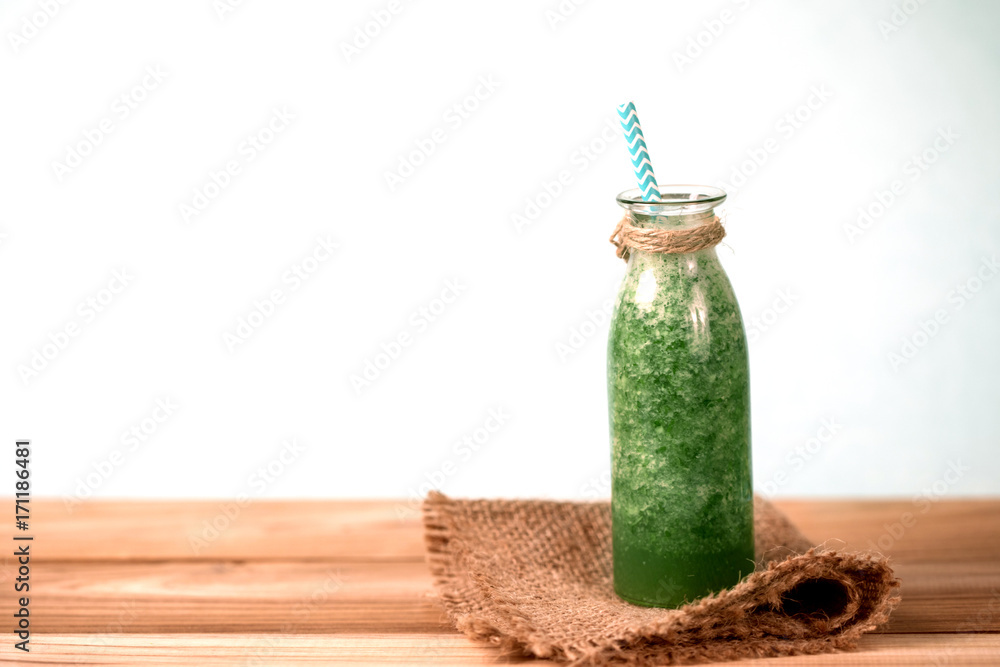 木桌上玻璃瓶装的健康新鲜绿色奶昔汁，用于健康排毒和饮食
