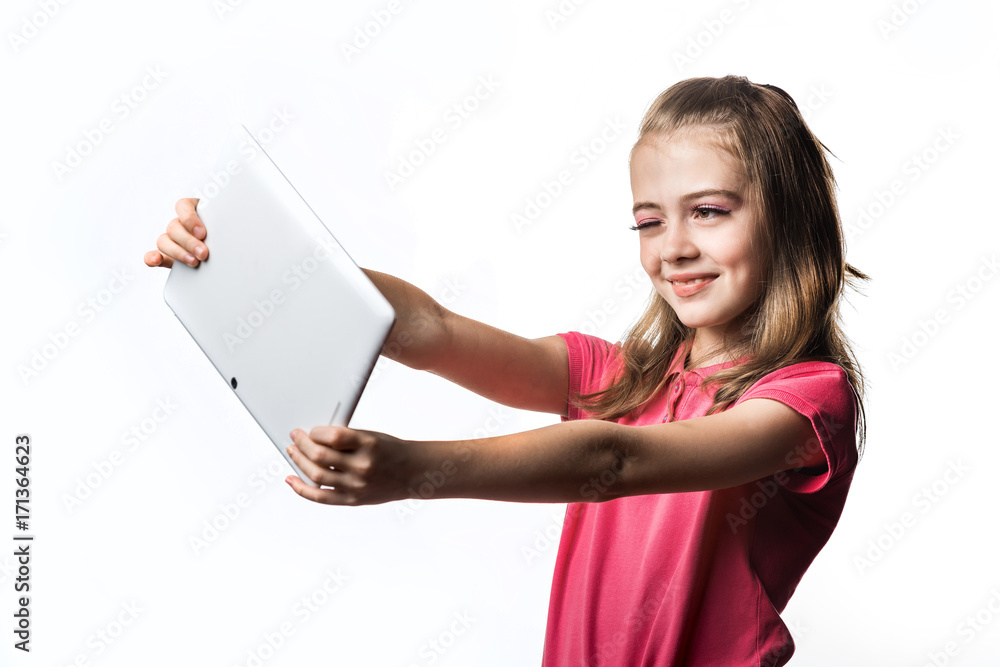 白色背景下拿着平板电脑的小女孩。孩子的表情和微笑。孩子的发展