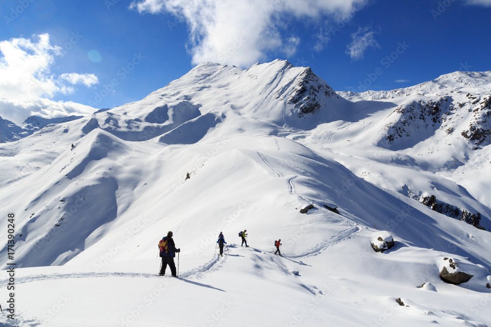 Group of people hiking on snowshoes and mountain snow panorama with blue sky in Stubai Alps, Austria