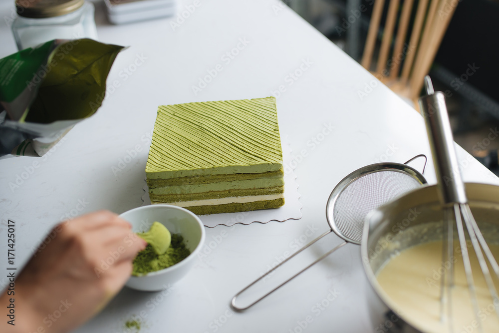 将绿茶粉浇在美味的芝士蛋糕上