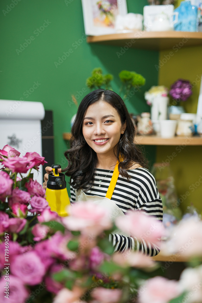 年轻漂亮的亚洲女孩花商在工作场所打理鲜花。
