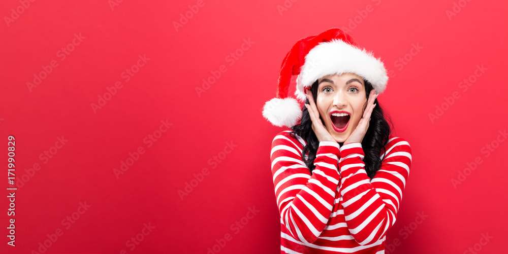 背景上戴着圣诞老人帽子的快乐年轻女人