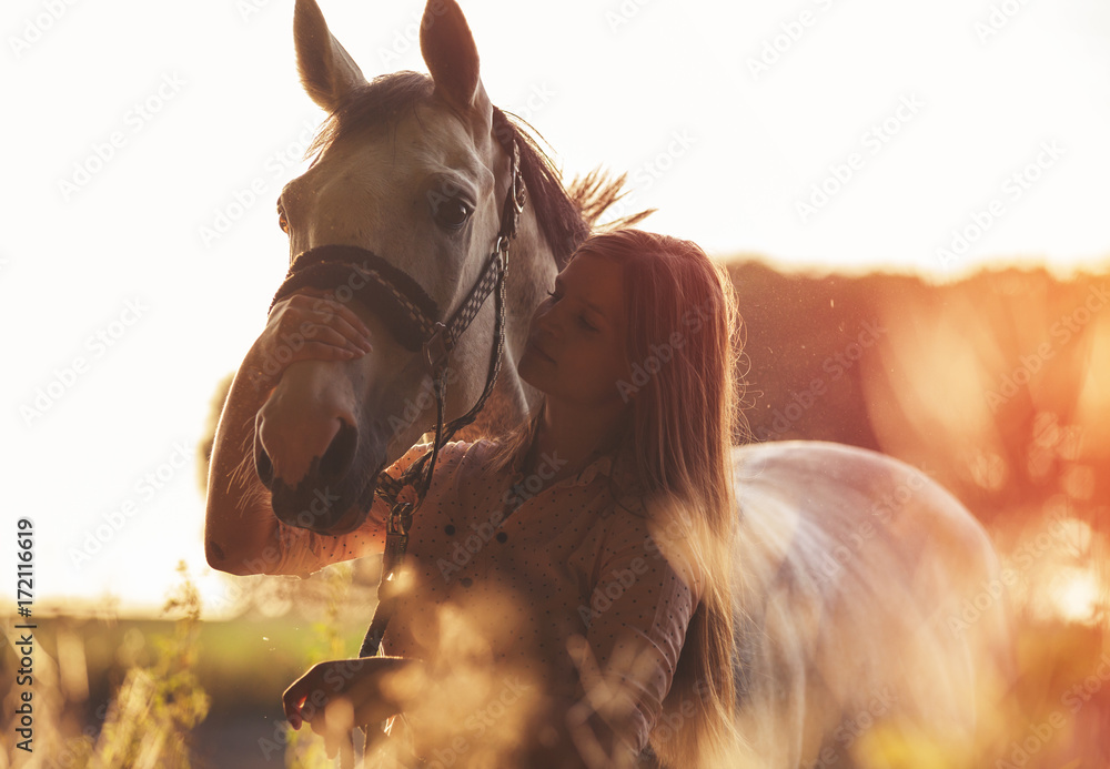 日落时分，秋天的场景，女人拥抱着她的马