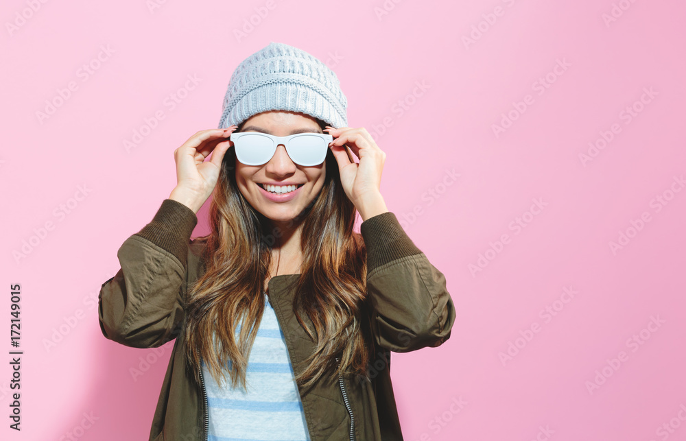 Fashionable girl wearing sunglasses and hat on a pink background