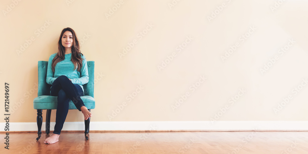 年轻的拉丁美洲女人坐在一个大的室内房间的椅子上