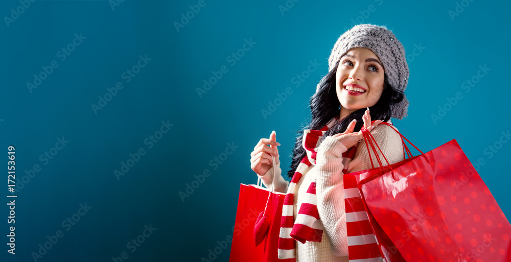 快乐的年轻女人在坚实的背景下拿着购物袋