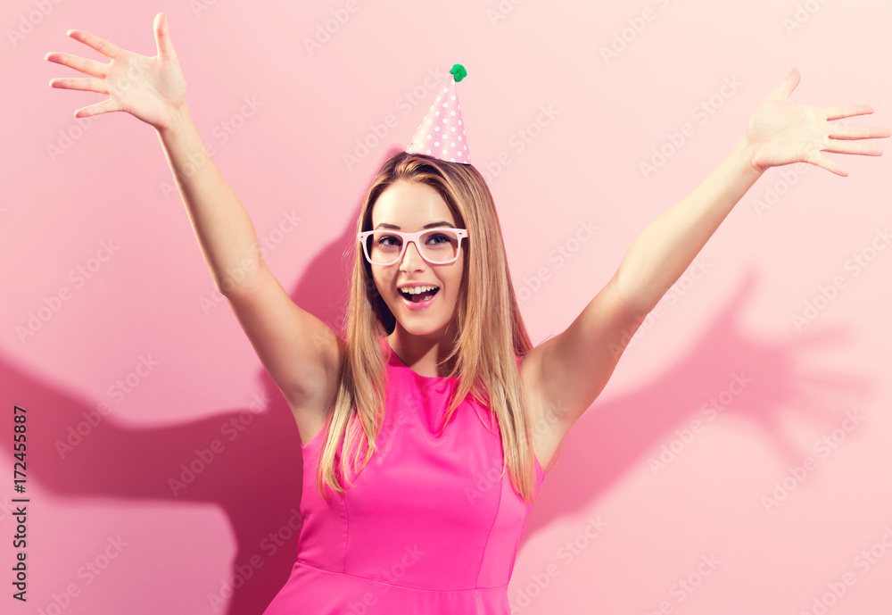 粉色背景戴派对帽的年轻女子