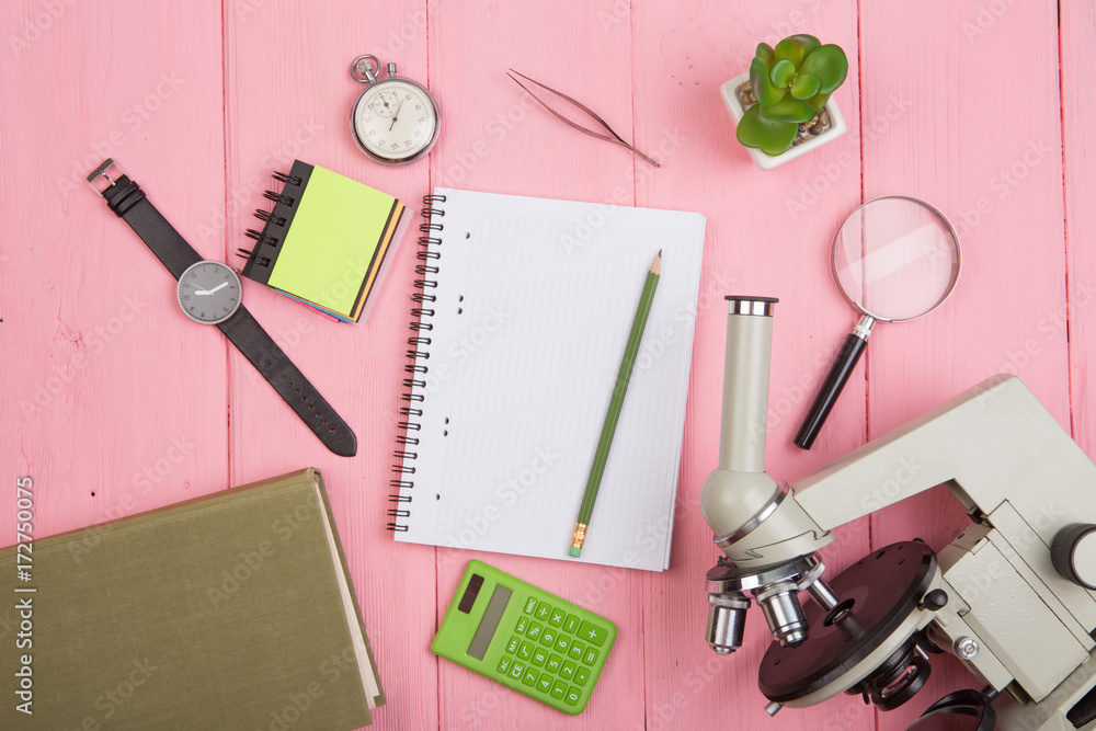 教育理念-笔记本，粉红色木制桌子上的显微镜