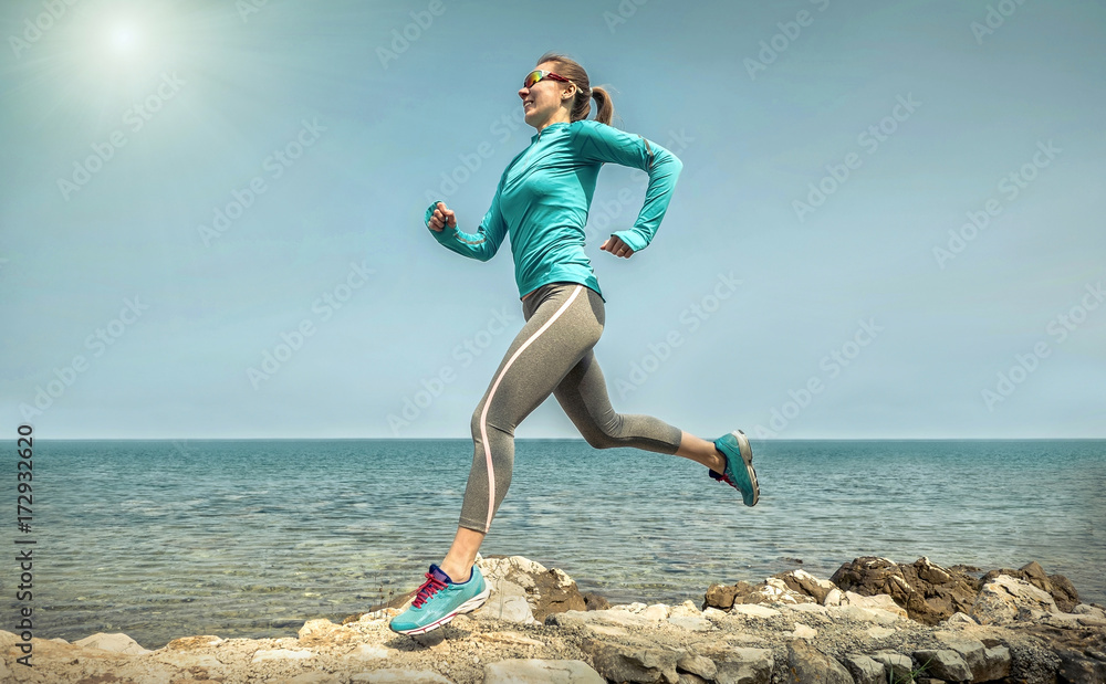 阳光明媚的苏，一名女子在阳光下沿着海岸线奔跑