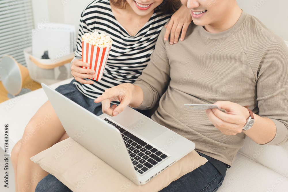 亚洲年轻夫妇使用笔记本电脑在线支付电影票