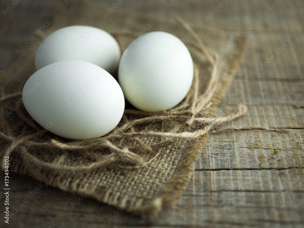 鸭蛋、白蛋、旧袋子上的带蛋黄的咸蛋和木制背景的绳子。