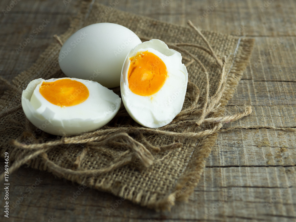 Duck eggs, white eggs, salted eggs with yolk on old sack and ropes with wooden background.
