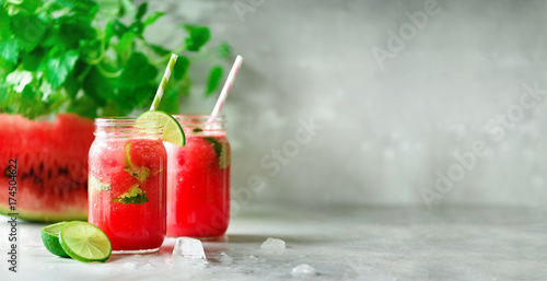 新鲜的红西瓜片和冰沙，在玻璃罐中加入吸管，冰，薄荷，酸橙，浅色背景