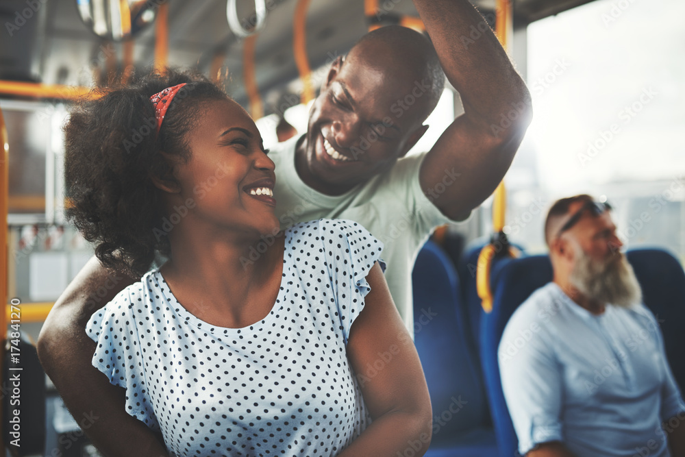 一对微笑的非洲年轻夫妇深情地站在公交车上