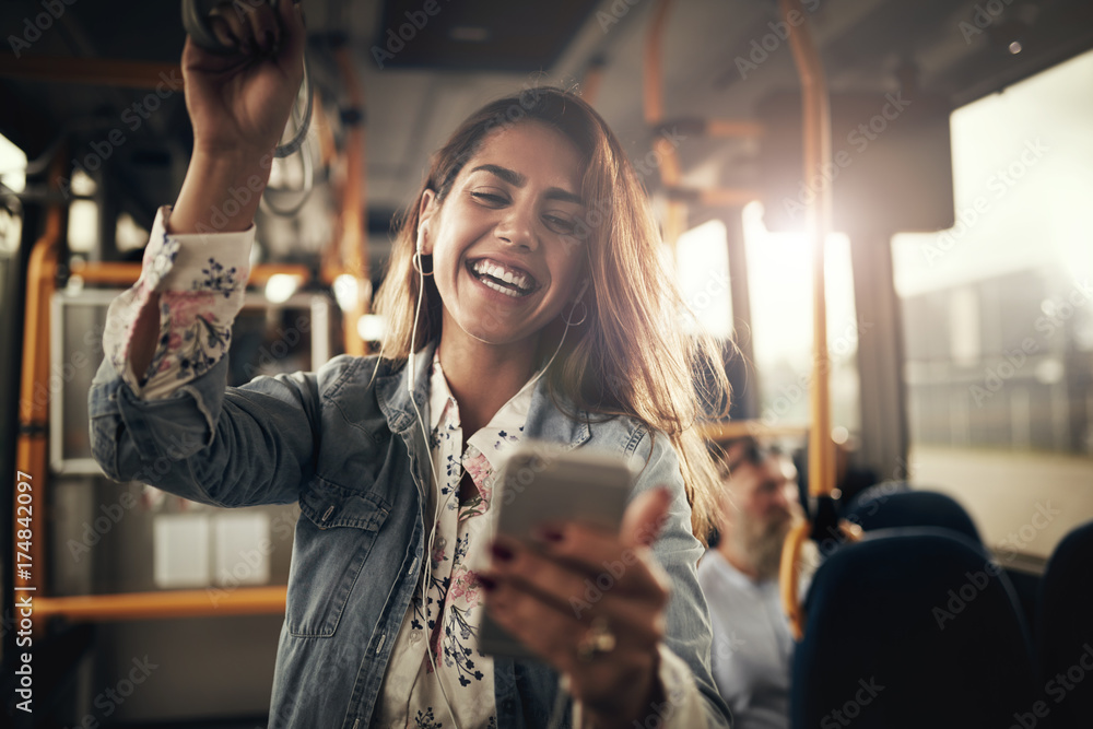 Laughing young woman listening to music on a bus