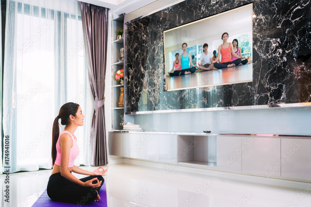 Asian lady start to training Yoga by follow coach in television in living room, in luxury mome.