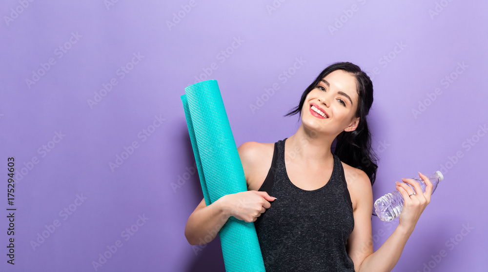 快乐的年轻女人拿着瑜伽垫