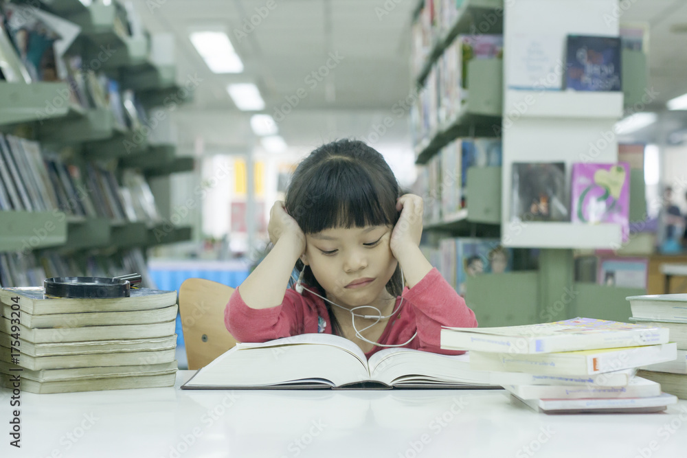 亚洲小女孩在图书馆看书感到无聊