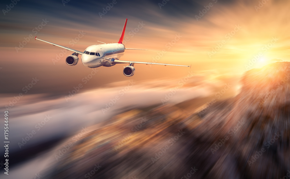 现代飞机的运动模糊效果在日落时飞越低云。风景如画