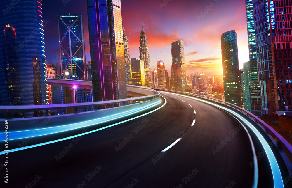 高速公路立交桥的运动模糊了城市天际线和城市摩天大楼，日落和黄昏的景象。