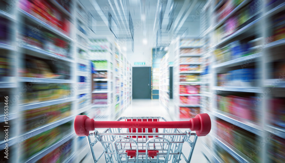 Red shopping cart with motion speed blurred .supermarket aisle background .