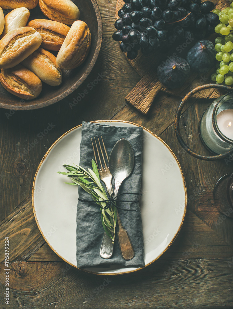 秋季节日餐桌装饰设置。盘子里有亚麻餐巾、叉子和勺子、蜡烛、新鲜水果