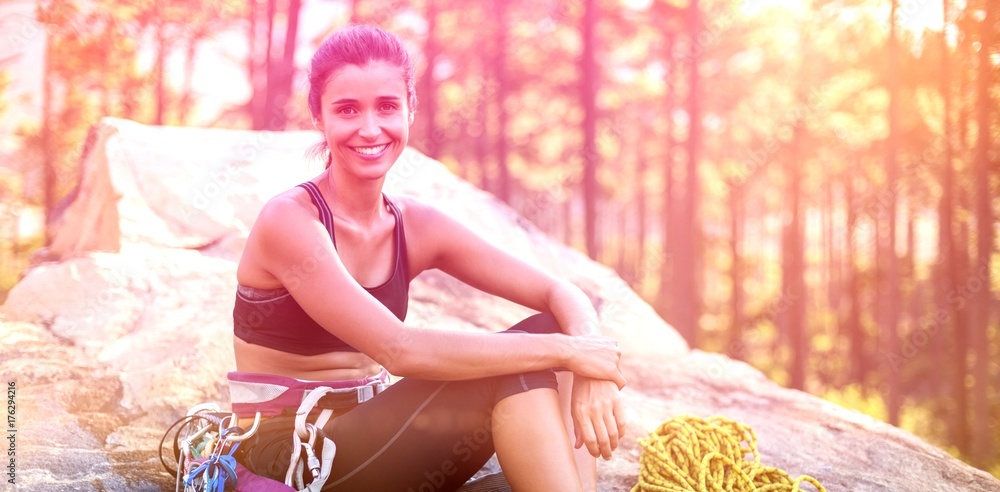 Woman smiling and sitting with climbing equipment 