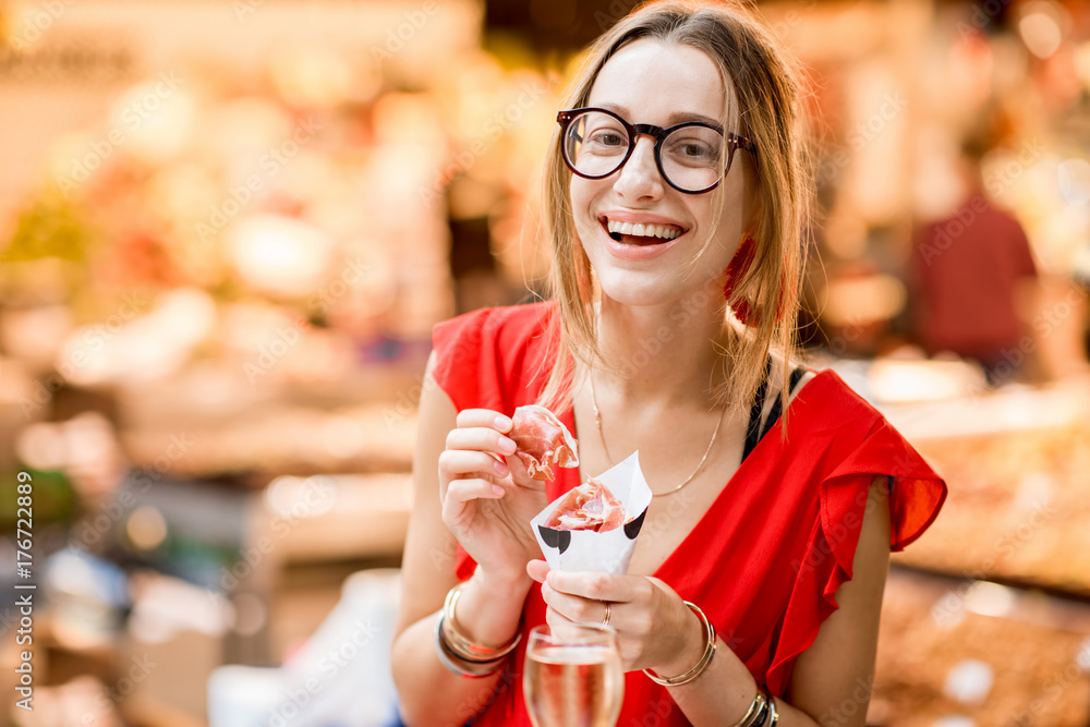 一位身穿红色连衣裙的年轻女子坐在餐厅吃着果酱传统西班牙干腌火腿的画像