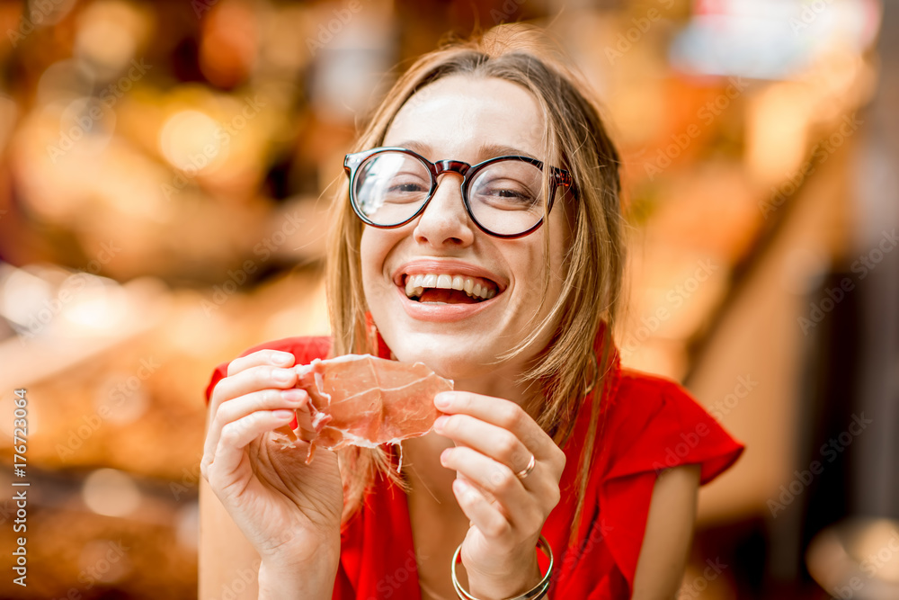 一位身穿红色连衣裙的年轻女子坐在巴塞罗那餐厅吃着传统的西班牙干腌火腿