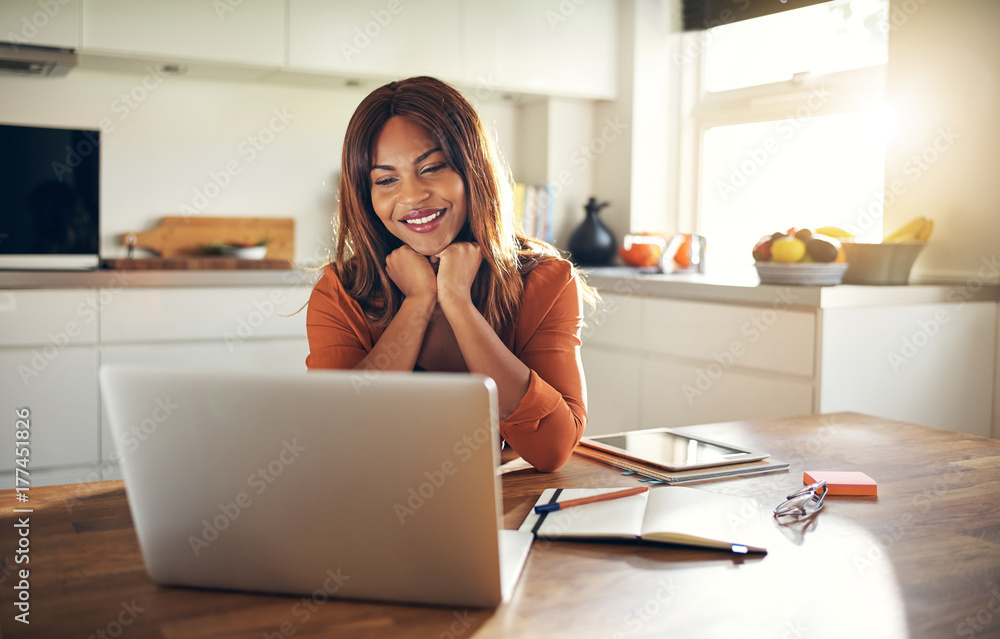 微笑的年轻女企业家在厨房里在线工作