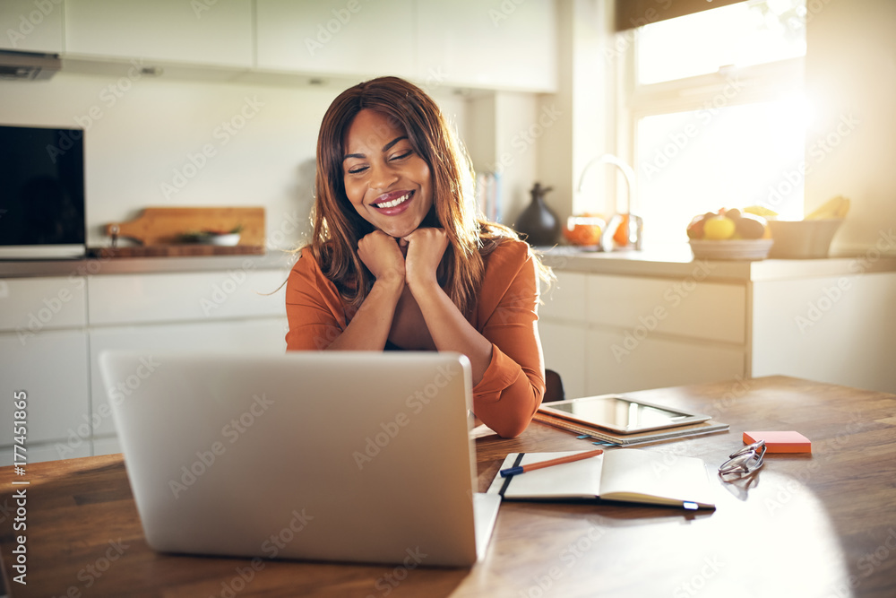 微笑的年轻企业家在厨房里用笔记本电脑工作