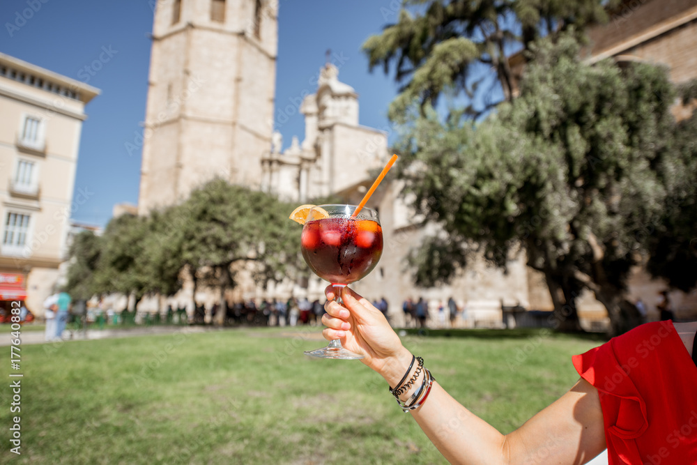 Holding a glass with sangria, traditional spanish alcohol drink, on the main cathedral bazckground i
