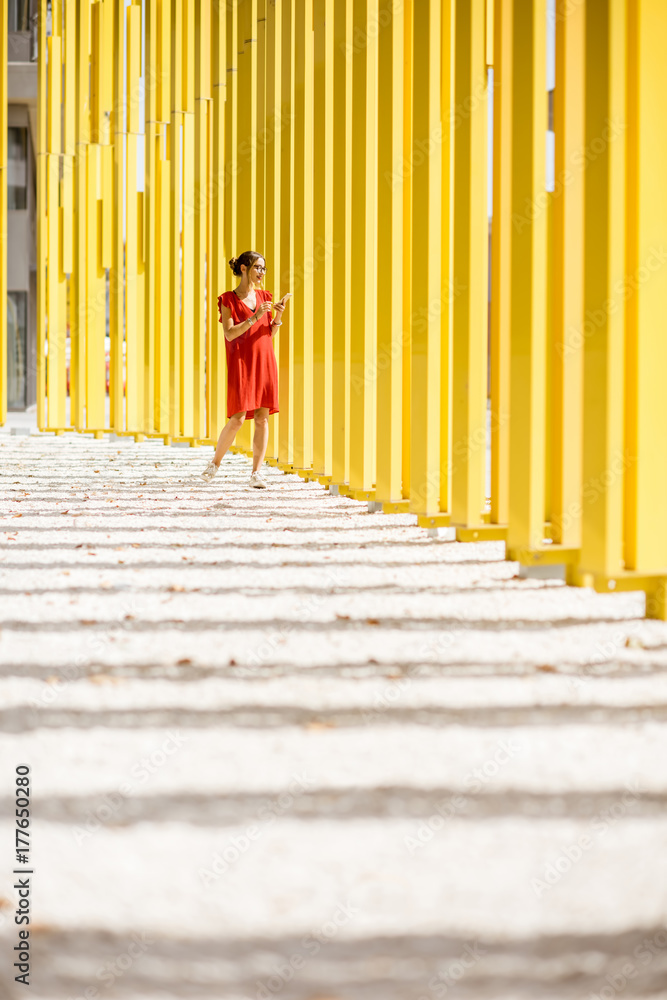 现代黄色建筑墙背景上穿着红色连衣裙的女人。抽象几何图形的总平面图