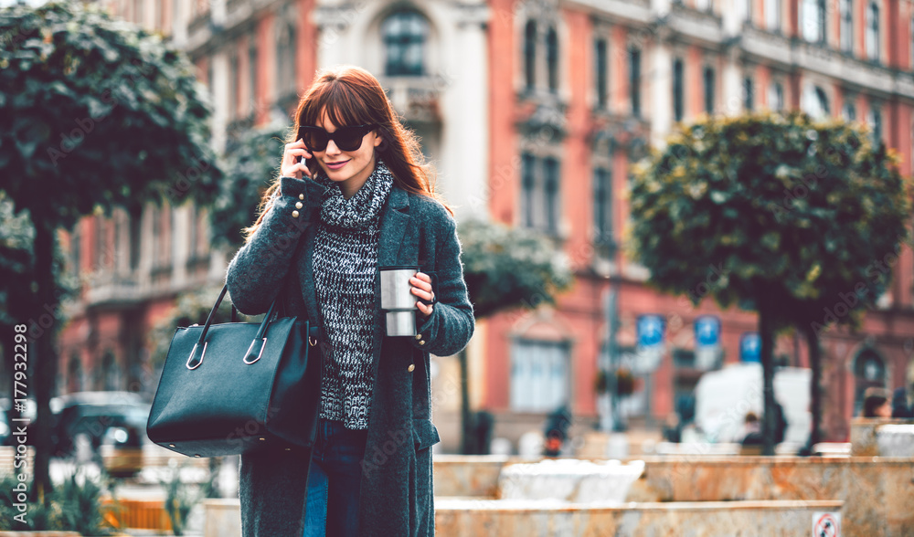 城市场景，一个拿着咖啡杯的女人在城市里用手机聊天