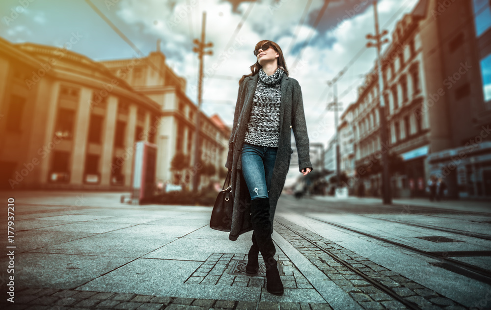 休闲时尚都市场景，穿着外套的时髦女人走在街上