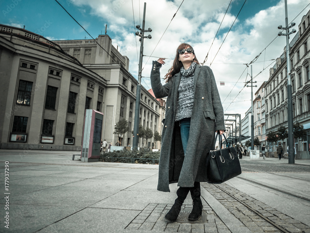 休闲时尚都市场景，穿着外套的时髦女人走在街上