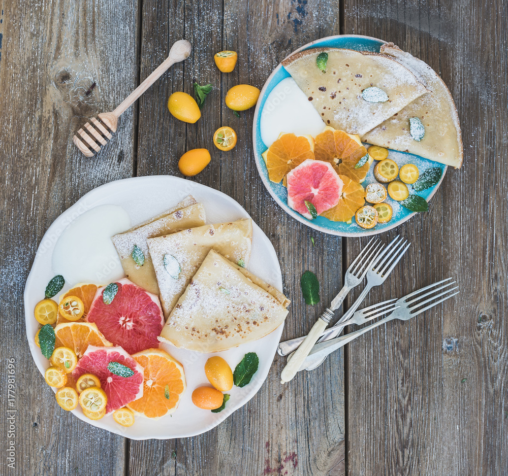 Spring vitamin breakfast set. Thin crepes or pancakes with fresh grapefruit, orange, kumquat, honey,