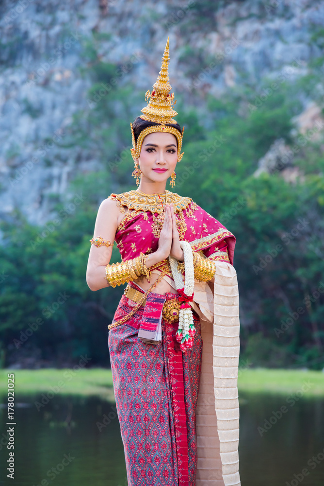 身穿泰国传统服饰的亚洲美女做着欢迎和微笑的手势