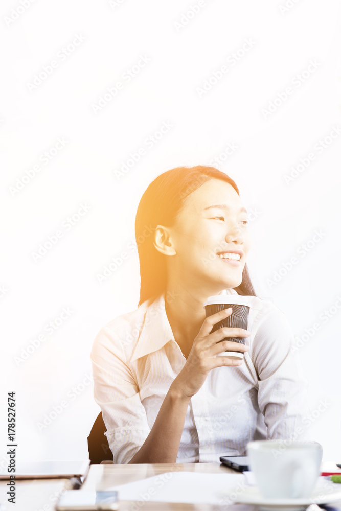 穿着白衬衫的亚洲女人喝着咖啡微笑幸福