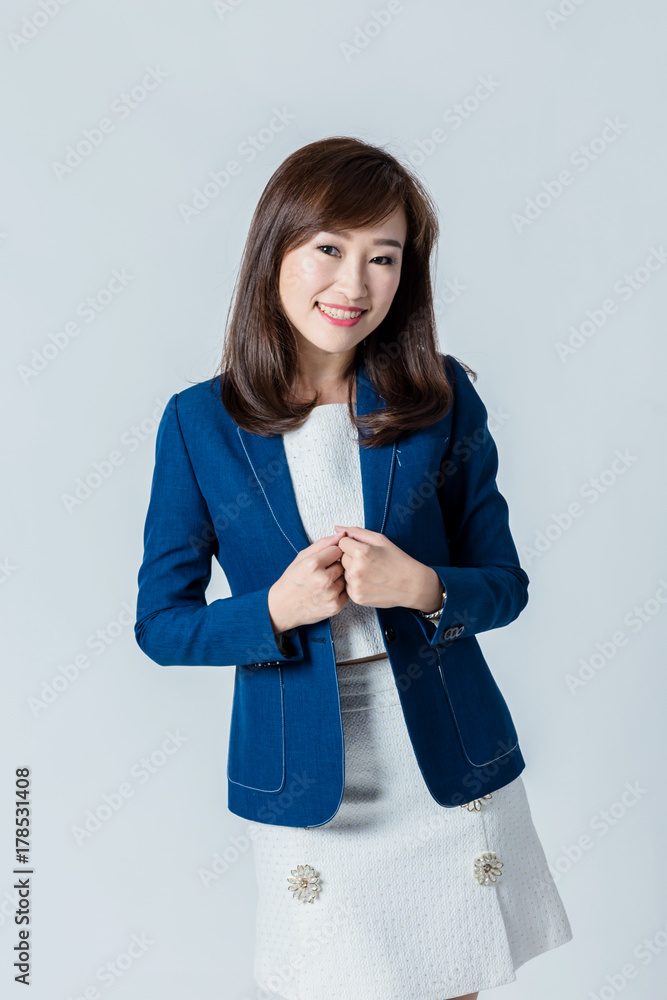 穿着蓝色西装的亚洲女人在工作室里摆出快乐的动作姿势，隔离白色背景