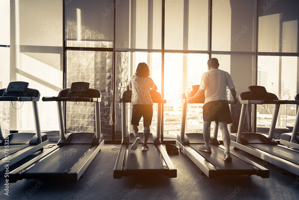 健康的男人和女人在健身房的跑步机上跑步。运动与健康概念