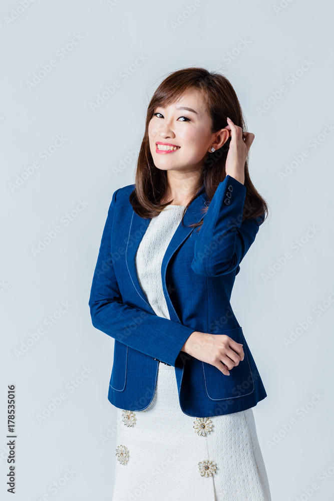 穿着蓝色西装的亚洲女人在工作室里摆出快乐的动作姿势，隔离白色背景