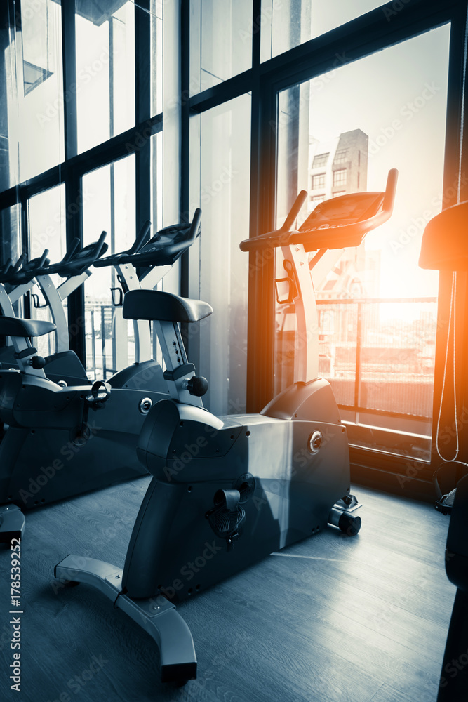 带设备的现代健身房内部。一排训练健身自行车车轮细节，阳光。健康