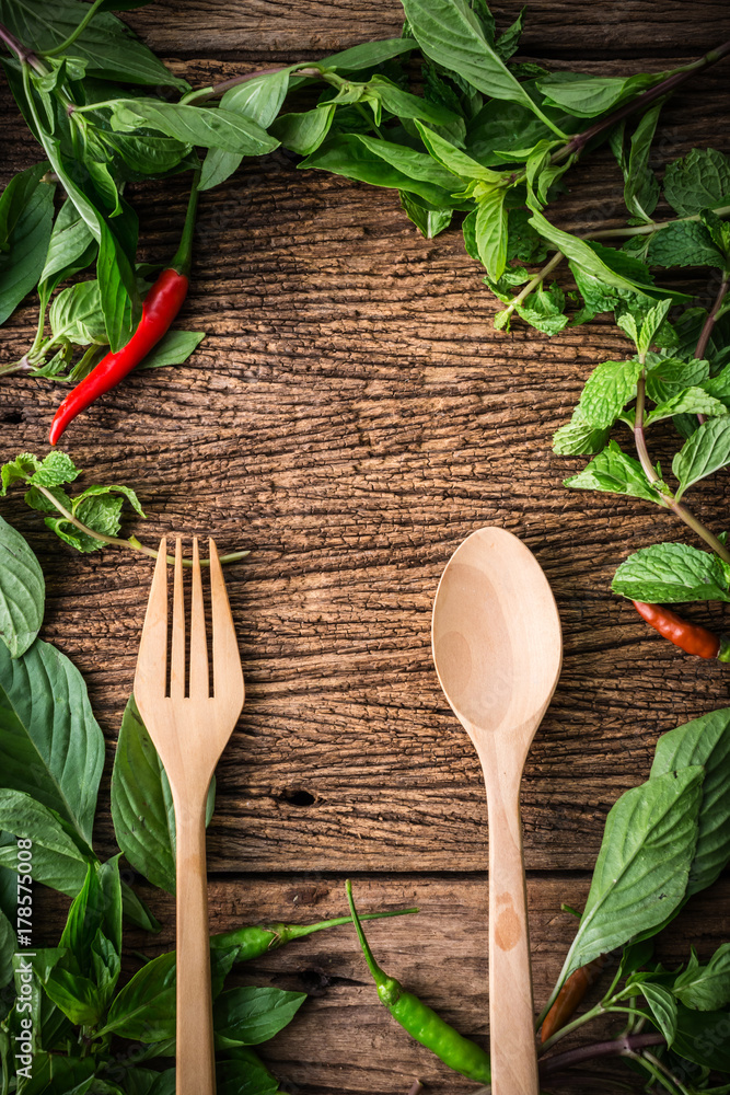 wooden spoon with chili and basil asian herb and in gredients on old vintage wooden texture backgrou