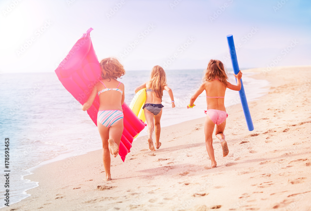 女孩们带着游泳工具在海边奔跑