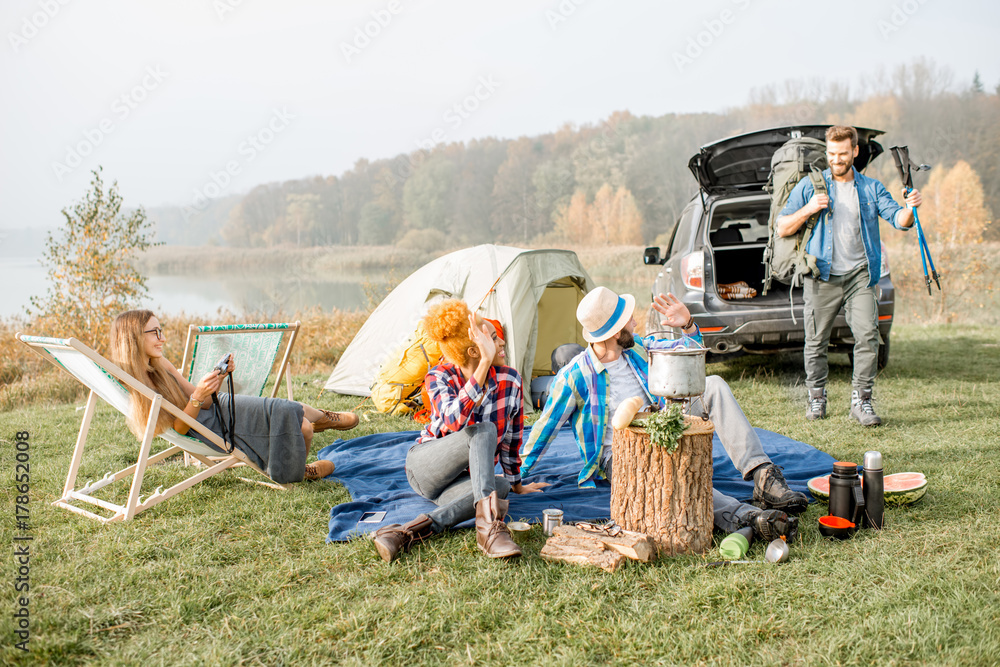 Multi ethnic group of friends dressed casually having a picnic during the outdoor recreation with te