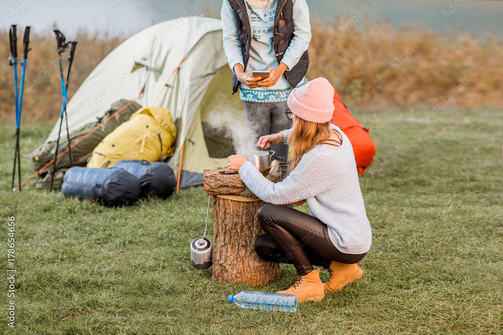 两名穿着毛衣的妇女在ev露营的户外娱乐活动中为晚餐烹饪食物