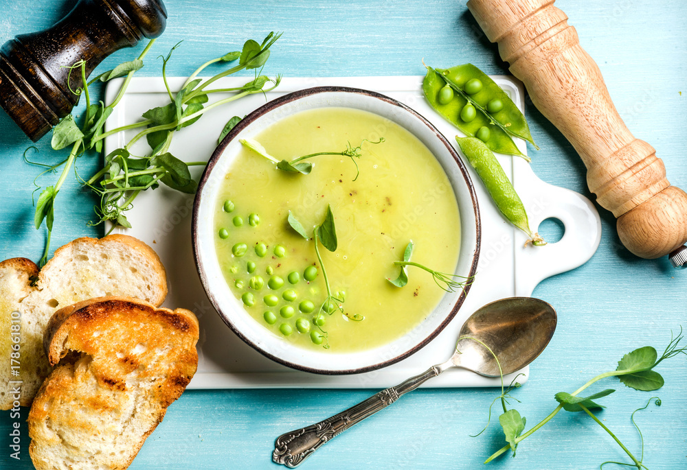 浅夏绿色豌豆奶油汤，碗里有芽菜、烤面包和香料。白色陶瓷板