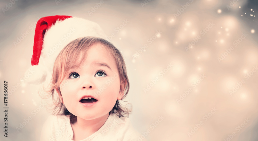 Happy toddler girl with Santa hat in snowy night